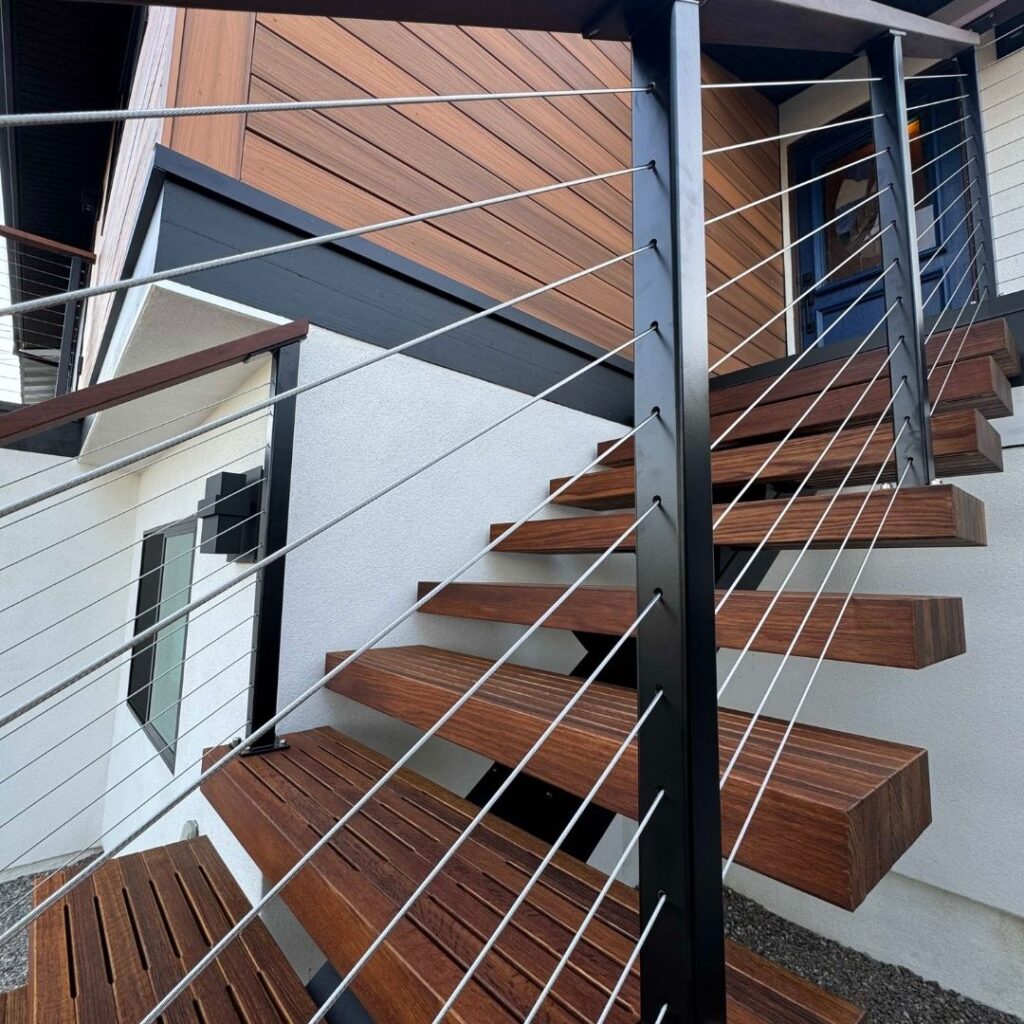 Close-up of thin stainless steel cables on a staircase railing highlighting the clear view of the room behind it.