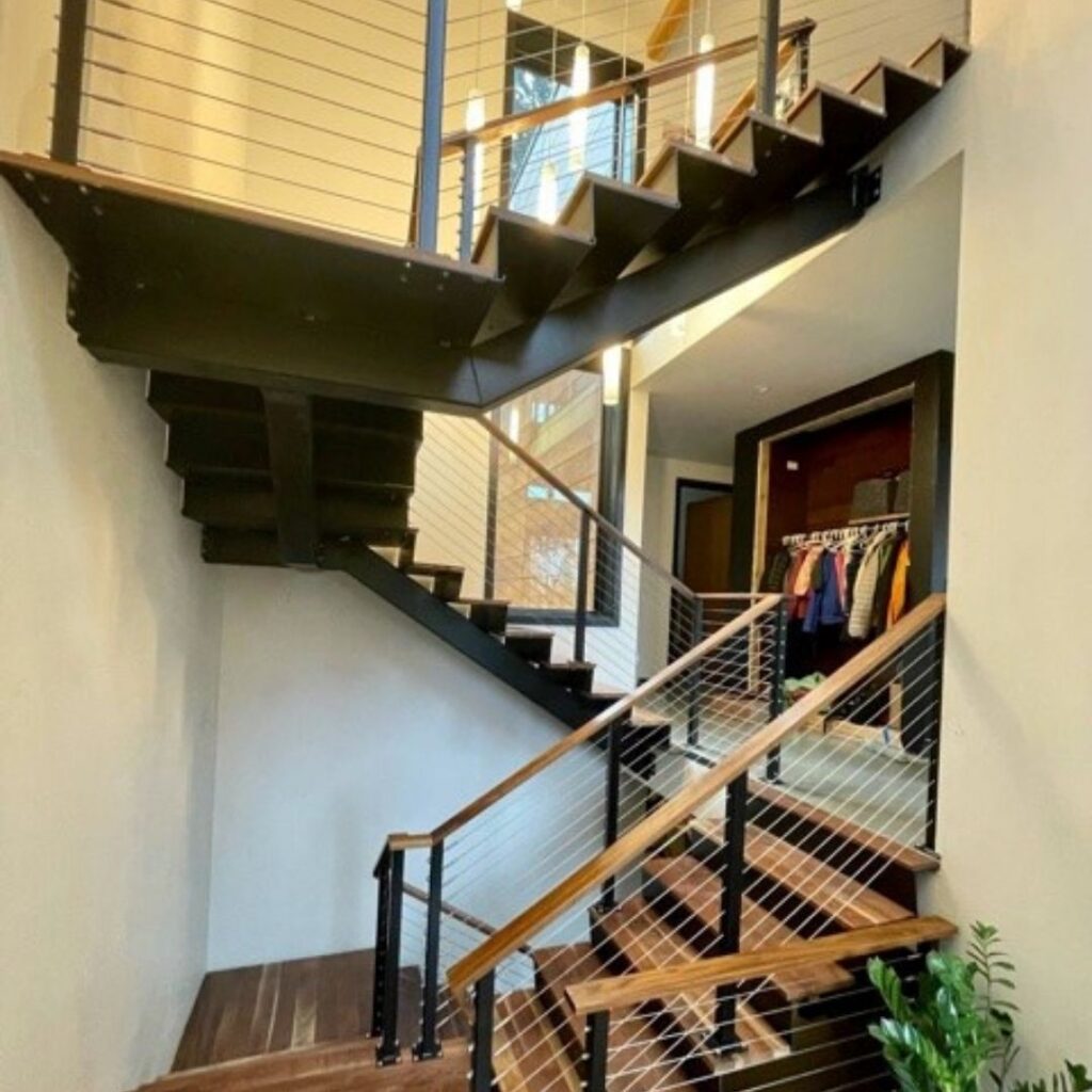A hand on a sturdy staircase handrail with secure cable railing infill, illustrating safety and stability.